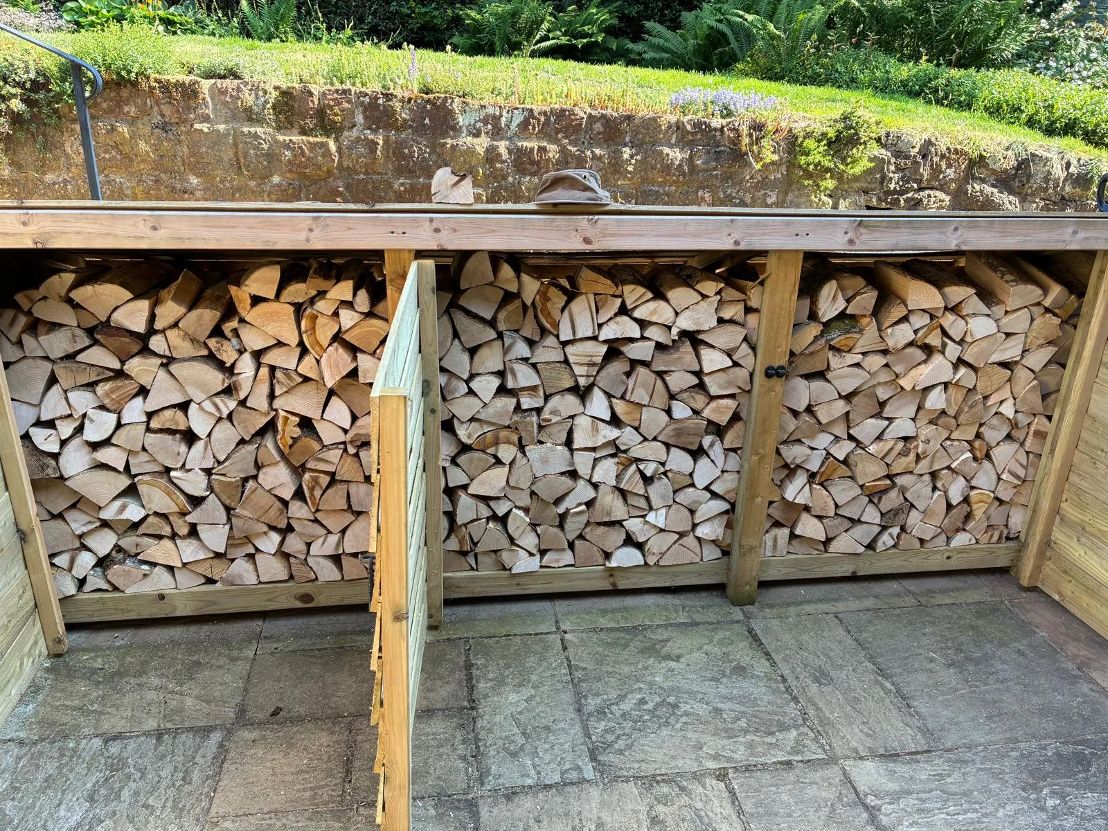 A pile of wood sitting next to a wooden fence.