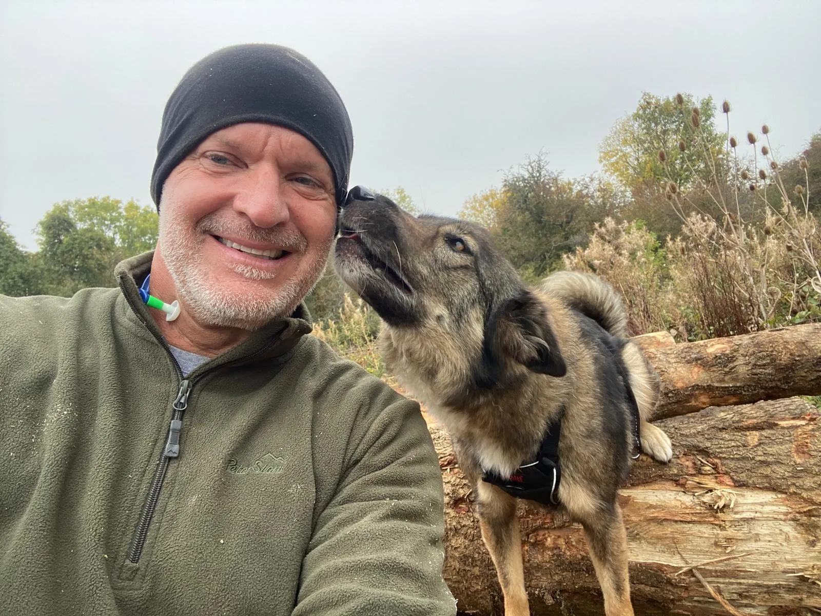 A man is giving a dog a kiss on the nose.